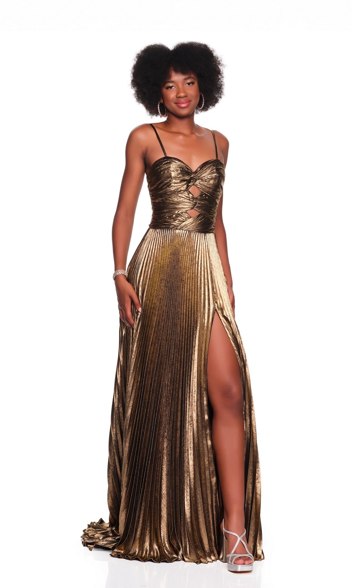 A woman models the Dave and Johnny 12449 long prom dress—a gold metallic pleated gown with spaghetti straps, an open back, and a high slit—standing against a white background.